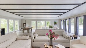 A spacious living room with a pool table, two sofas, a coffee table, and large windows offering a view of the outdoors. - Amber Refresh by Avantstay Pool and Hot Tub (New Market)