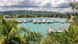 Un port de plaisance où de nombreux bateaux sont amarrés, entouré d’une végétation luxuriante et avec des collines en arrière-plan.