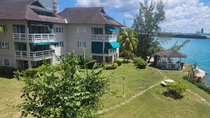 Un immeuble à plusieurs étages doté de balcons, d’un jardin agrémenté d’un belvédère et offrant une vue sur l’eau.