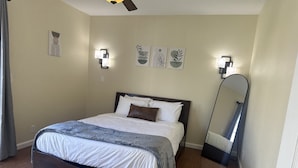 Een opgeruimde slaapkamer met een bed, bedlampjes en wanddecoratie.