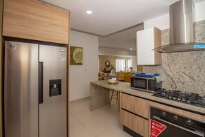 A modern kitchen with stainless steel appliances, a granite countertop, and wooden cabinetry.