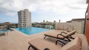 Uma área de piscina no terraço com espreguiçadeiras e vista para a cidade.