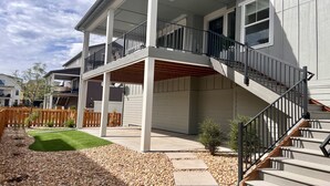 A two-story house with a covered patio, a wooden deck, and a staircase leading to the upper floor. - New Modern Stylish Oasis, Bright and Comfortable Home (Parker)