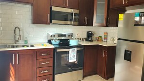 A kitchen with dark wooden cabinets, stainless steel appliances including a microwave, stove, and refrigerator, and a tiled backsplash.