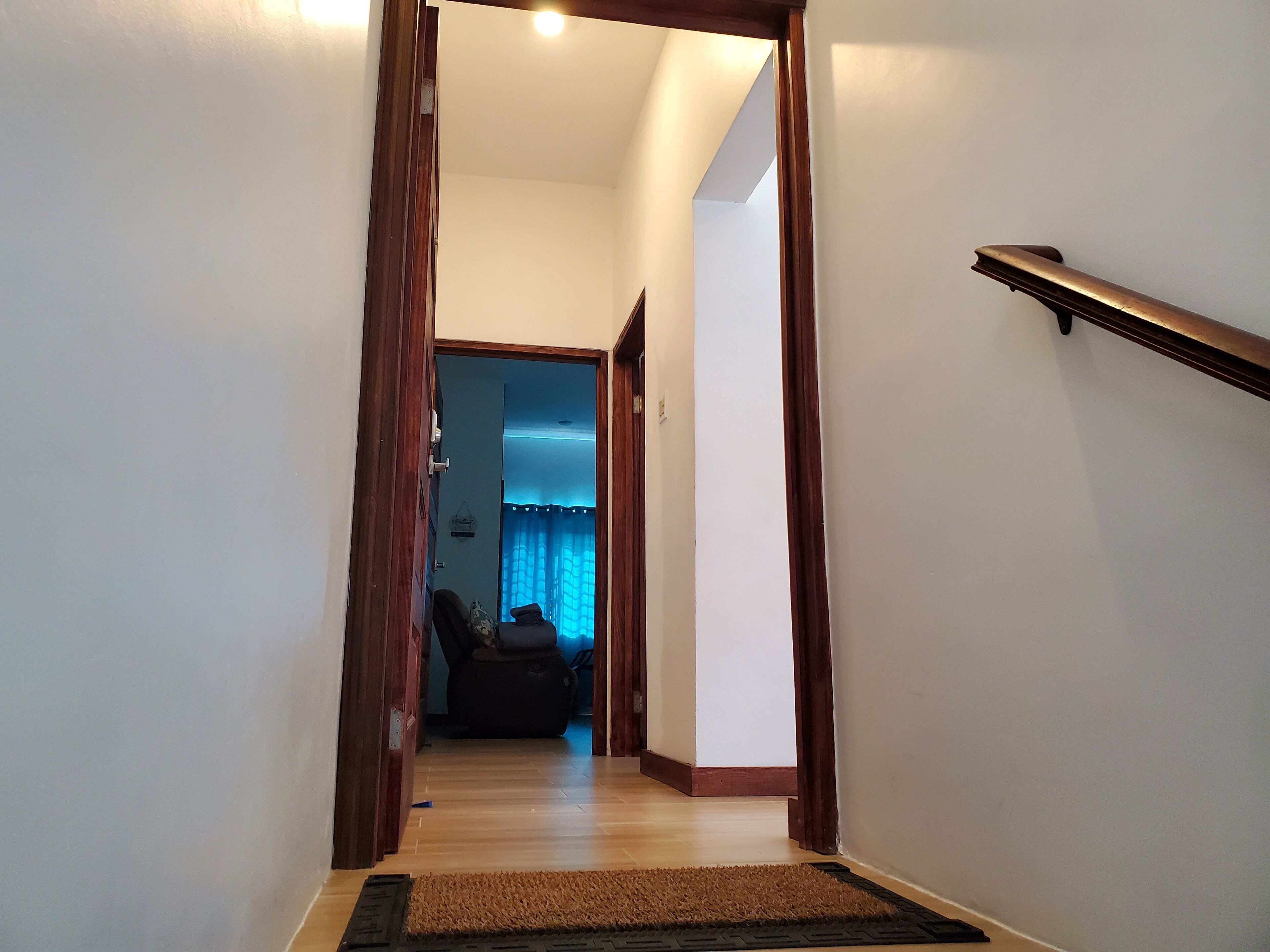 Un couloir avec des portes en bois menant à une pièce où est suspendu un rideau bleu.