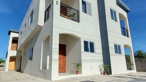 A modern two-story building with a flat roof, large windows, and a balcony.