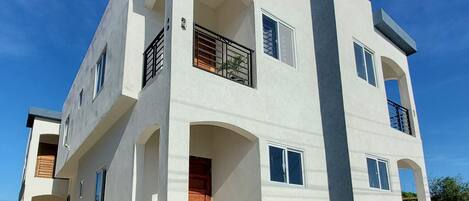 A modern two-story building with a flat roof, large windows, and a balcony.