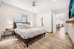 Un dormitorio con una cama grande, mesitas de noche, un ventanal y vistas al comedor.