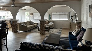 A living room with a wooden ceiling, stone pillars, a sofa, a blue couch, and a coffee table. - FISHERMANS DREAM HOUSE (Big Pine Key)