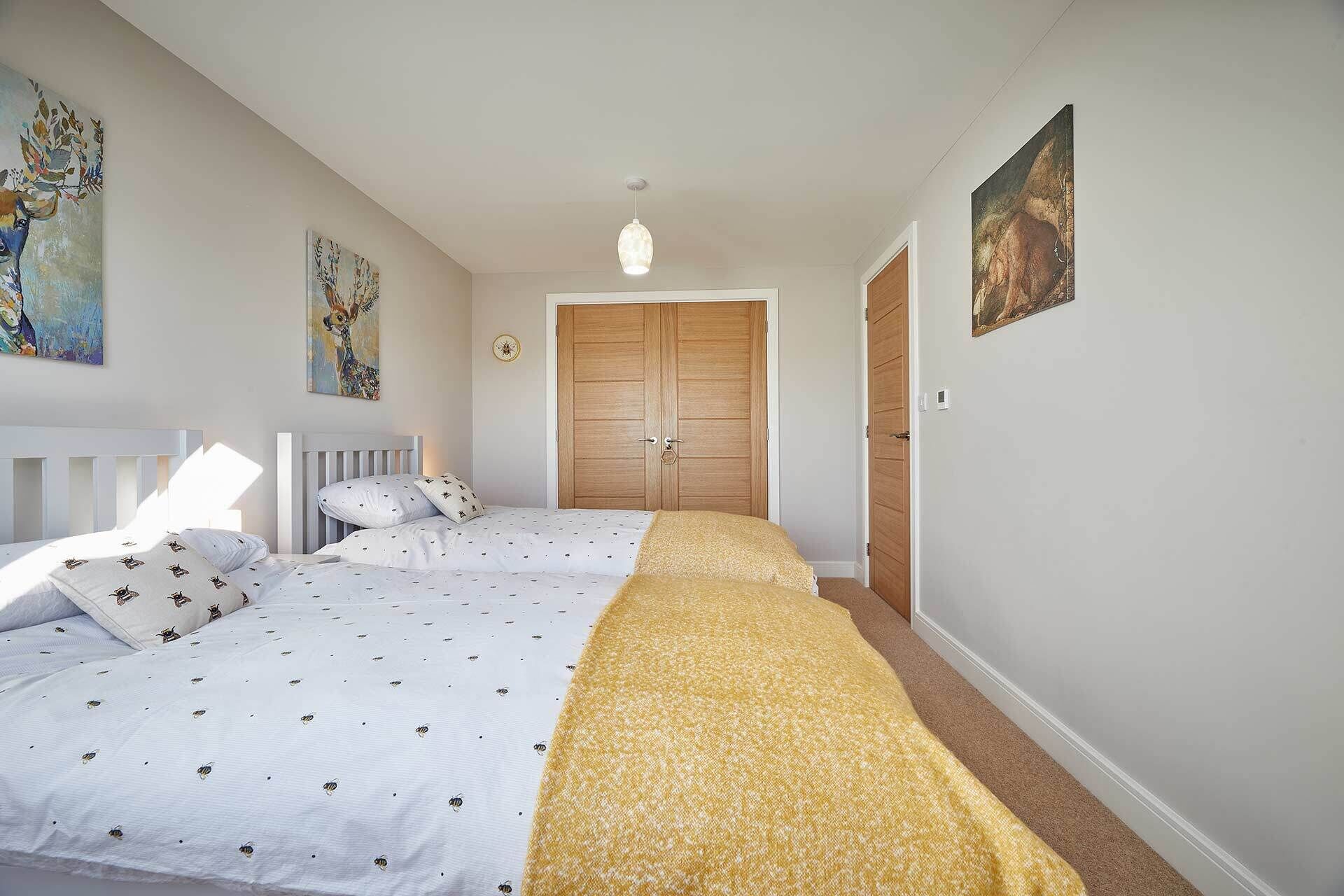 Un dormitorio con dos camas, un armario de madera y obras de arte en las paredes.