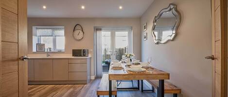 Een moderne keuken met een eetgedeelte, houten vloeren en uitzicht.
