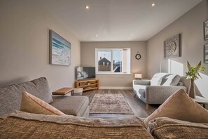 A living room with a sofa, a TV, a window, and a decorative plant. - Host Stay Sunflower Cottage (Seahouses)