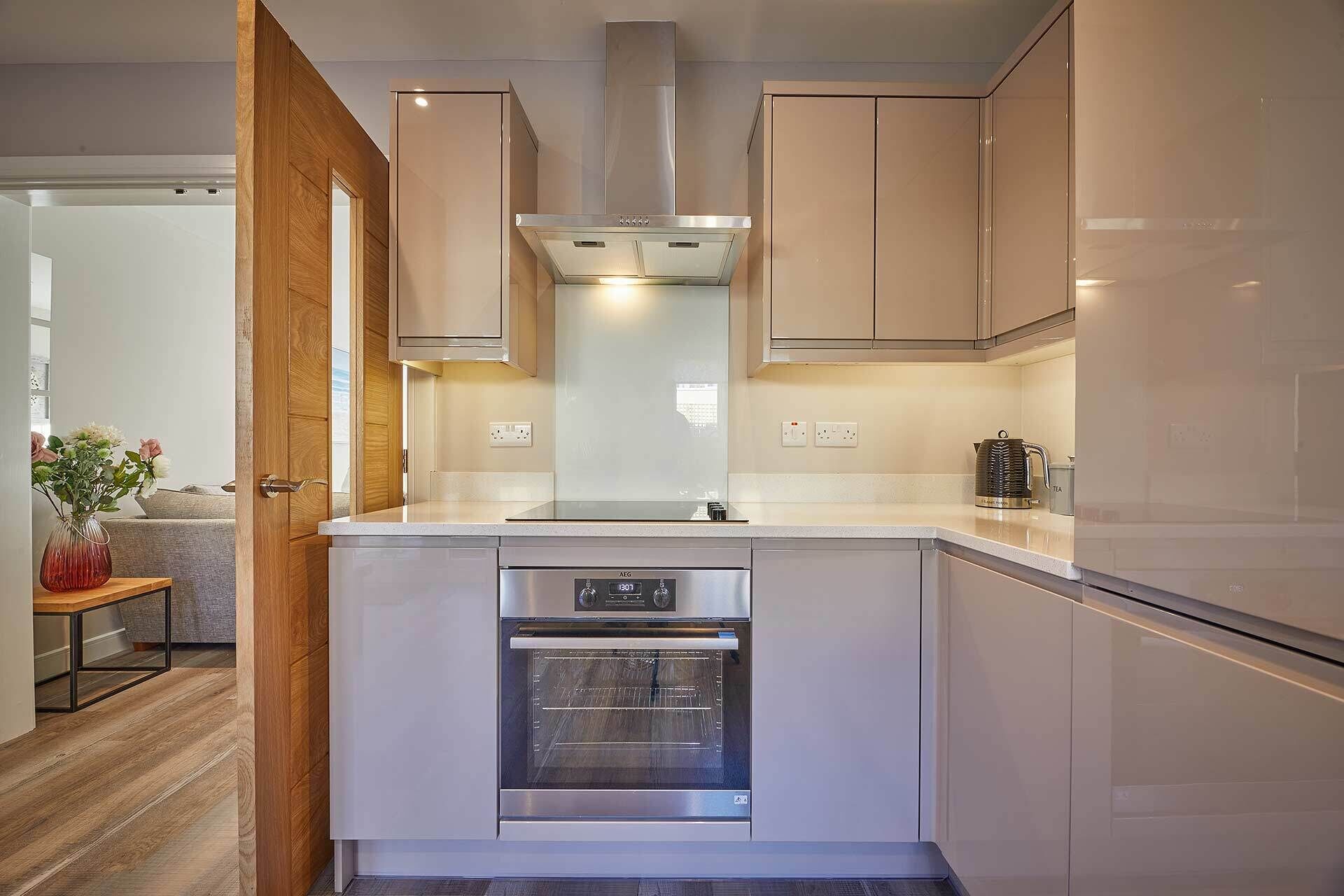 A modern kitchen with a built-in oven, stainless steel appliances, and wooden cabinetry.