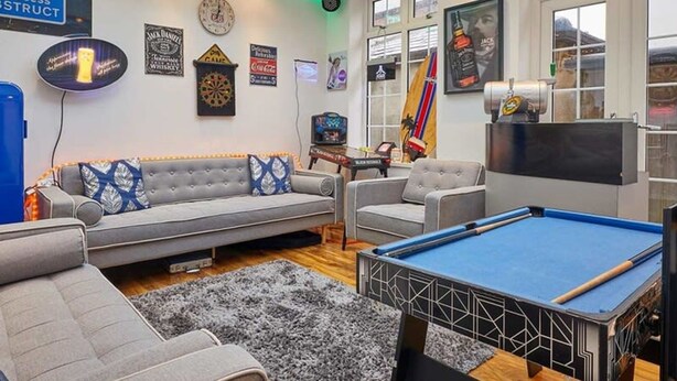 Un salon moderne avec une table de billard, des canapés et un jeu de fléchettes.