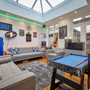 A modern living room with a pool table, sofas, and a dartboard. - Host Stay The View Old Coastguard Cottage (North Shields)