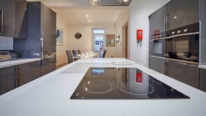 Une cuisine moderne dotée d’un îlot central, d’appareils électroménagers en acier inoxydable et d’un coin repas à l’arrière-plan.