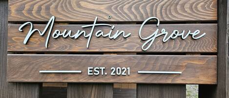 En träskylt med texten ”Mountain Grove, grundat 2021” på ett trästaket.