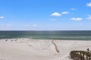 A beach with a clear sky, a sandy shore, and a few umbrellas. - "Island Palm - Luxury 2BR/2BA Beachfront Condo (Panama City)