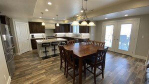 Una cocina amplia con una isla grande, armarios de madera oscura y una zona de comedor con mesa y sillas de madera.