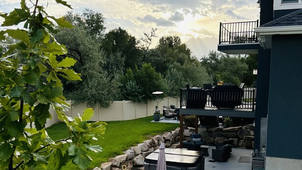 Un patio con mobiliario exterior, una parrilla y vistas al jardín trasero.