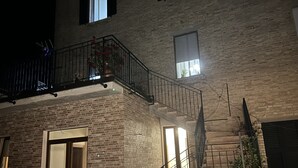 En murstensbygning med balkon, trappe og dør til et indre rum.