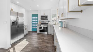 A modern kitchen with white cabinetry, stainless steel appliances, and a wooden floor. - Charming El Cajon Retreat  (El Cajon)