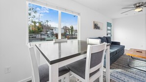 A modern living room with a dining table, white chairs, a sofa, and a ceiling fan. - Charming El Cajon Retreat  (El Cajon)