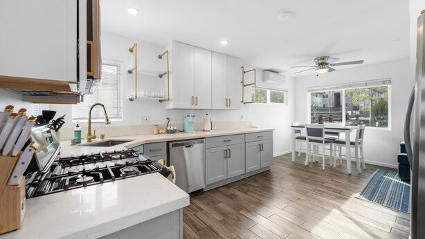 A modern kitchen with white cabinets, a stainless steel refrigerator, and a dining area with a table and chairs. - Charming El Cajon Retreat  (El Cajon)