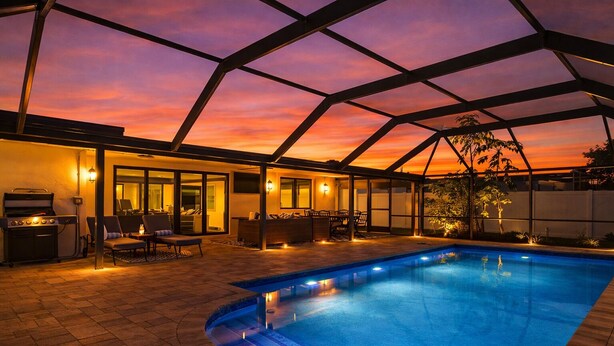 Una piscina interior con vistas al atardecer, un área de barbacoa y una zona de estar con vista a la piscina.