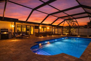 Ein Innenpool mit Sonnenuntergangsblick, ein Barbereich und eine Sitzgelegenheit mit Blick auf den Pool.