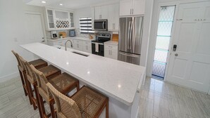 Una cocina moderna con armarios blancos, electrodomésticos de acero inoxidable y una isla grande con taburetes de bar.