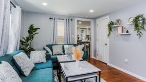 A modern living room with teal sofas, patterned cushions, a marble coffee table, and a large plant. - 2 BEDROOM APARTMENT IN BRISTOL NEAR PLAINVILLE  (Bristol)