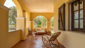 Une terrasse couverte avec un canapé, des fauteuils et une chaise berçante.