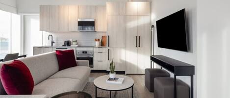 A modern living room with a sofa, coffee table, and a flat-screen TV mounted on the wall.