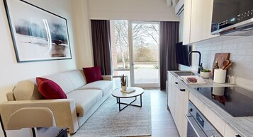 A modern living room with a sofa, a coffee table, and a kitchen area with a TV and cabinets.