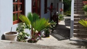 Un bâtiment à deux étages doté d’un patio couvert, de plantes en pot et d’un escalier menant à l’étage supérieur.