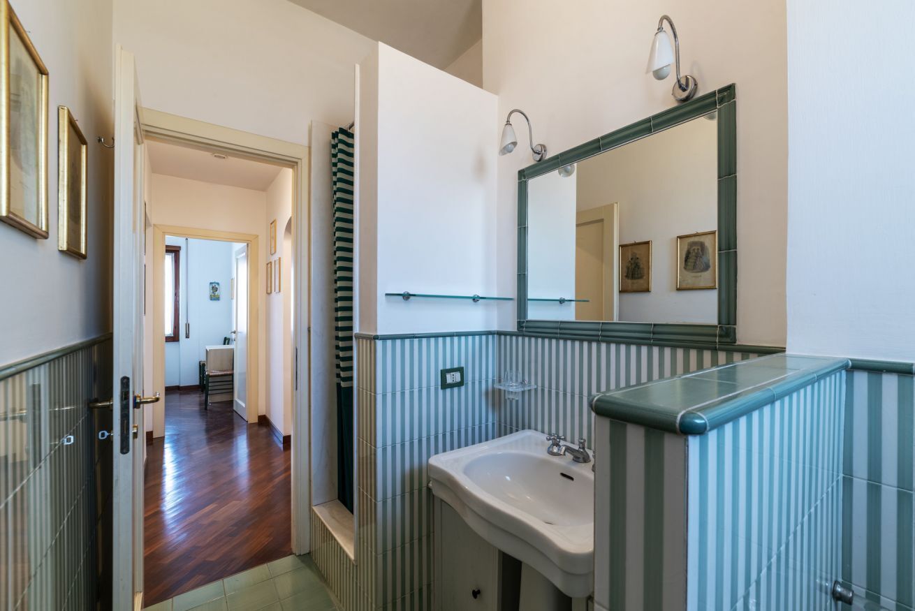 Une salle de bain avec un lavabo, un miroir et des murs à rayures.