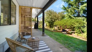 A covered porch with wicker furniture and a striped rug. - Modern 1 Bed Suite Close to Town & Westwood Lake (Nanaimo)