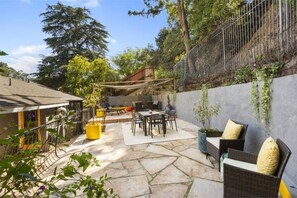 Relax in a serene outdoor space with a dining table, sofa, and armchairs.