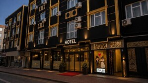 Un hotel con fachada negra, varias unidades de aire acondicionado y una entrada con alfombra roja.