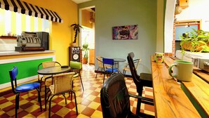 A restaurant with a checkered floor, a counter with a cash register, and chairs around a table. - Ding-Dong Hostel (Cali)