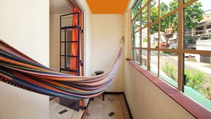 A narrow hallway with a hammock hanging from the ceiling, a window with a view of the street, and a door with a curtain. - Ding-Dong Hostel (Cali)