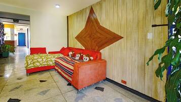 A hotel lobby with a red sofa, a patterned bed, and a large wooden wall decoration.