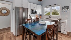 Una cocina moderna con armarios blancos, electrodomésticos de acero inoxidable y una mesa de comedor de madera.