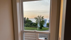 Ein Fenster mit Blick auf eine Wiese und ein Gewässer.