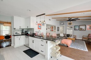 A modern kitchen with white cabinets, a black countertop, and a ceiling fan.