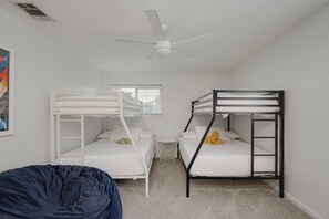 Una habitación con dos literas, un ventilador de techo y una mesita pequeña.