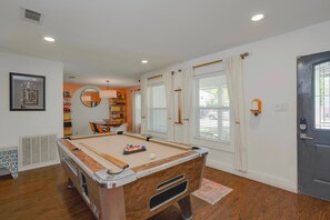A pool table in a room with a door, windows, and a bookshelf. - ATX Retreat • N. Central • Pool Spa Grill Sundeck Golf Pad• 15 min to Downtown (Austin)