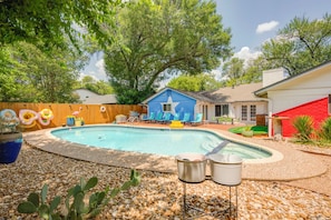 A backyard with a swimming pool, a blue house, and a red garage.