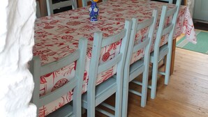 Un comedor con una mesa dispuesta para seis personas, rodeada de seis sillas con estampado rojo y blanco. Un jarrón con flores está sobre la mesa.
